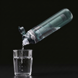 Bouteille filtrante de survie 750 ml versant de l'eau filtrée dans un verre SURVIVRA