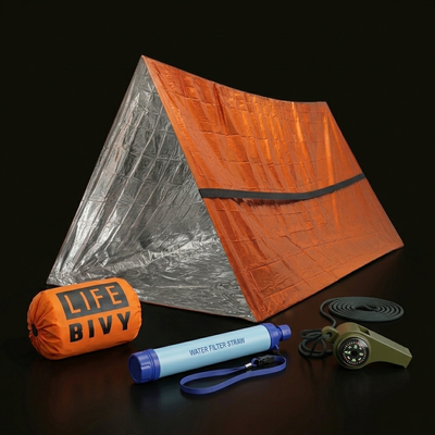 Coffret Le Marcheur SURVIVRA sur fond studio : tente de survie déployée, sac de couchage mylar, paille filtrante et sifflet 3-en-1